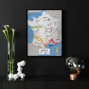 Framed wine map of France on a black wall, next to modern decor.