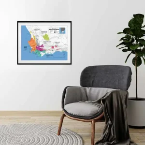 Framed South Africa wine map above a grey armchair in a minimalist room.