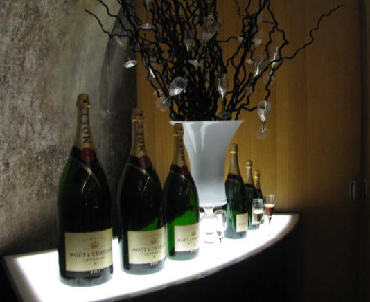 A display of large champagne bottles, arranged in a row on a softly lit surface.