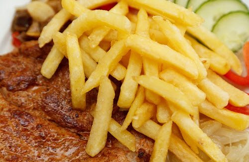 A close up of fries, steak and a side salad.