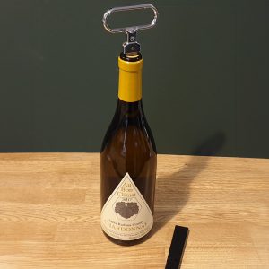 Bottle of Au Bon Climat Chardonnay with a metal corkscrew on top.