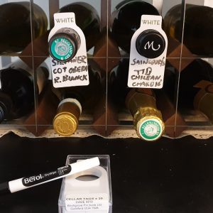 Wine bottles organised in a storage rack with labels indicating different types and origins.