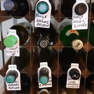 Wine bottles organised in a storage rack with labels indicating different types and origins.