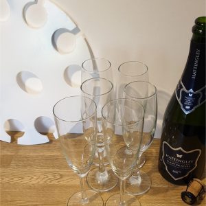 Champagne glasses on a table with a modern tray and a bottle of Hattingley Blanc de Noirs.