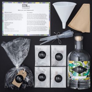 Overhead view of a GIN etc. Hedgerow Kit with a bottle, botanicals, funnel, pipettes, and instruction card on a black background.