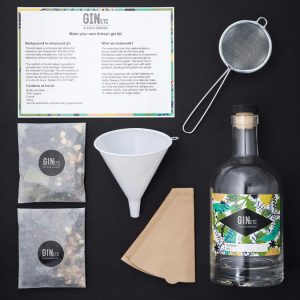 Artisan gin kit with a bottle, funnel, strainer, and botanicals, ready for gin crafting.