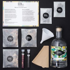 Gin-making kit with bottle, botanicals, and instructions on a black background.