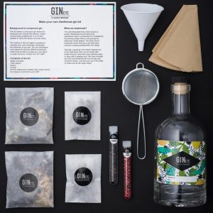 Contents of the GinEtc Gentleman gin kit, including botanicals, bottle, funnel, strainer, and instruction card.