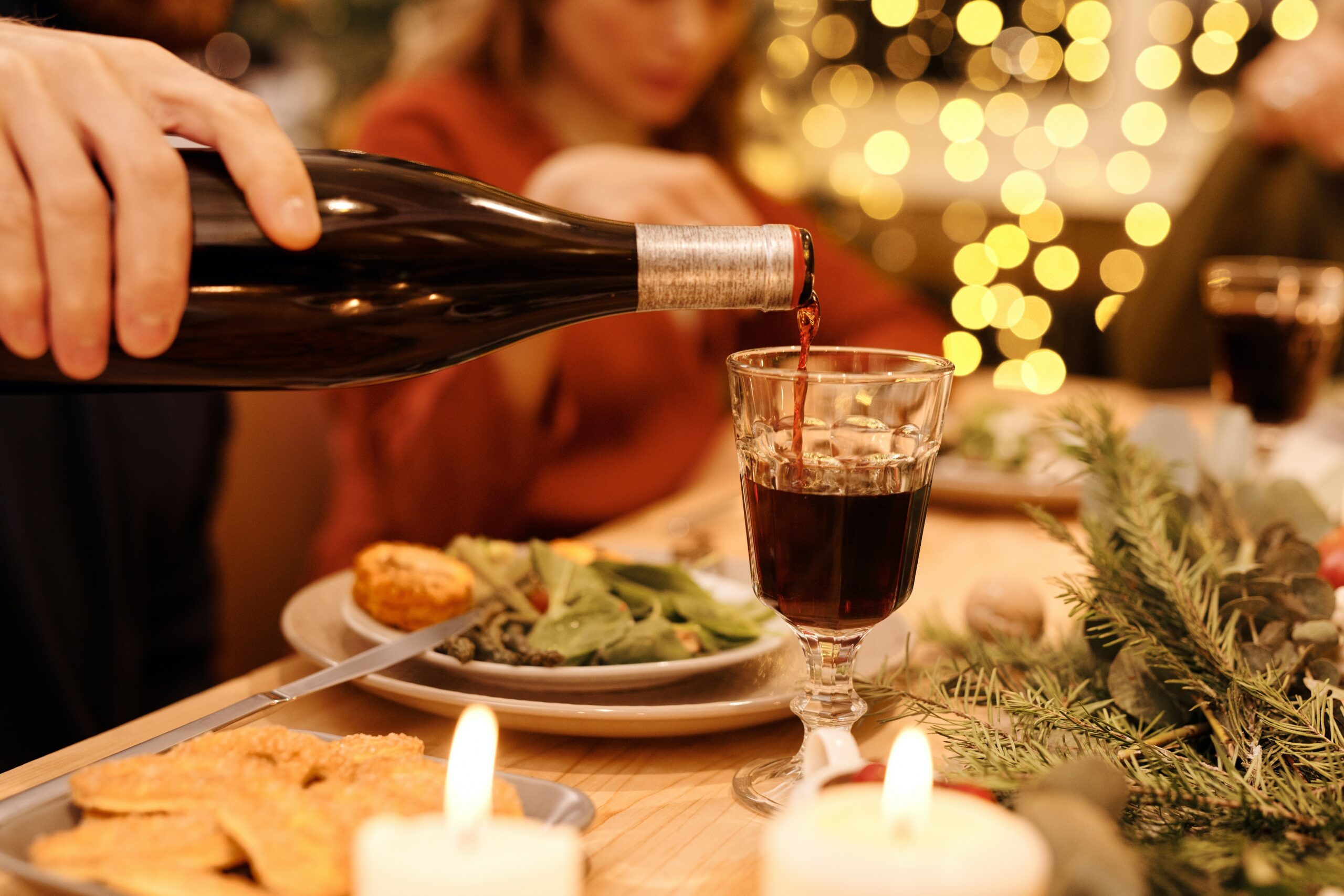 Someone pouring a glass of wine while at dinner.