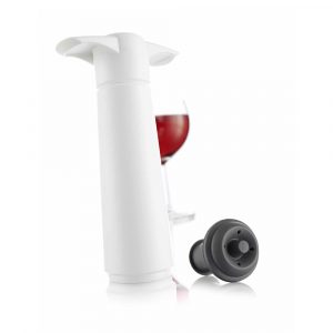 White wine preservation pump with a grey stopper, with a glass of red wine in the background.