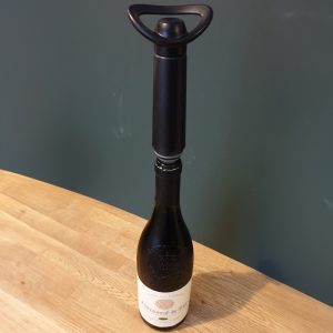 A wine bottle with a vacuum stopper and pump inserted, ready for sealing.