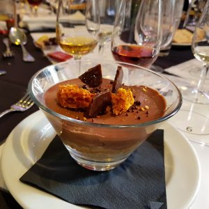 Chocolate mousse dessert with honeycomb and chocolate shards on a formal dining table.