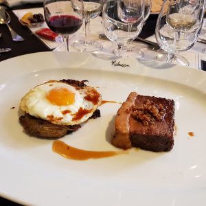 Fine dining plate with a gourmet dish, accompanied by a glass of red wine.