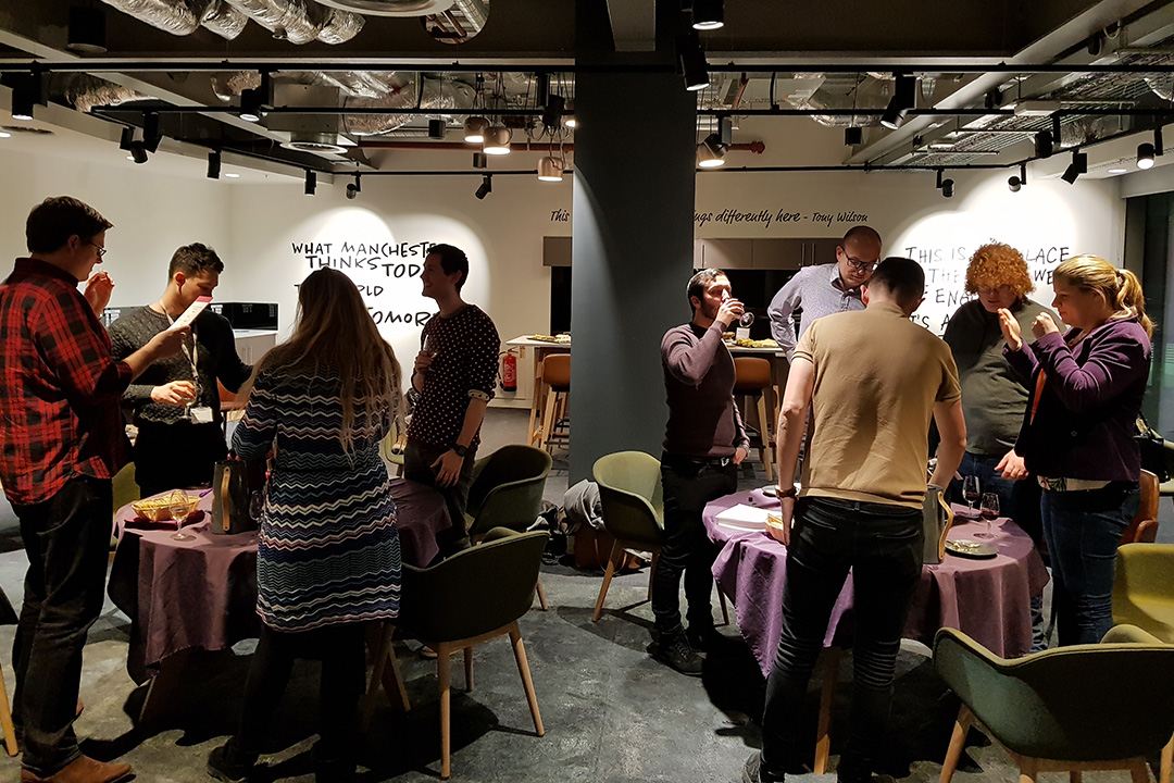 A group of people stood around two tables tasting different wines.