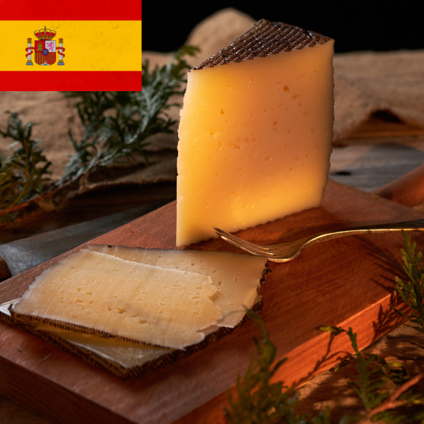 A wedge of Spanish Manchego cheese on a wooden board with a small fork, featuring the Spanish flag in the corner.